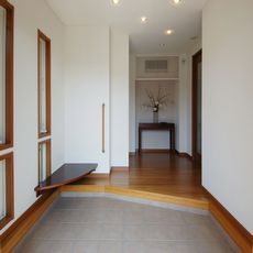 笠原の家：ゆったりとした玄関の入隅空間を利用して靴脱ぎ履き用の固定ベンチ「ウオールナット単板貼」造作
