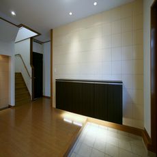 伊丹の家：壁面にバランスの取れた長さのシューズボックス・下部に間接照明の柔らかな灯りと天井面にダウンライトで壁面を照らす