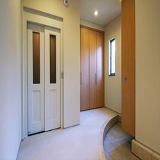 千葉稲毛の家：エレベーター採用の玄関ホールに土間収納と雑多収納を円を描いた上がり框奥に配する