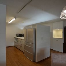 アンティークに囲まれるすまい：壁面収納と冷蔵庫壁上部間接照明内蔵
